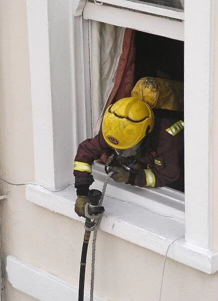 Firefighter using a rope to pull a hose up a building