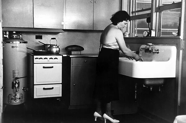 HOMESTEAD KITCHEN, 1936. Homesteader washing dishes in the kitchen of her new home