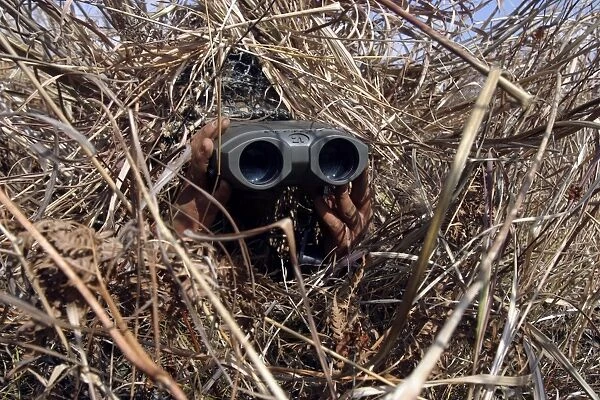 A scout observer practices observation techniques using a homemade ghillie suit
