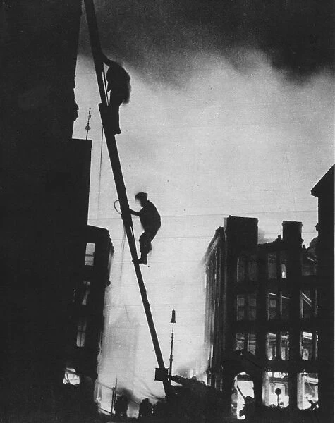Out in the Blitz, silhouetted aganinst the light of fires, rescue men climb into a building in St