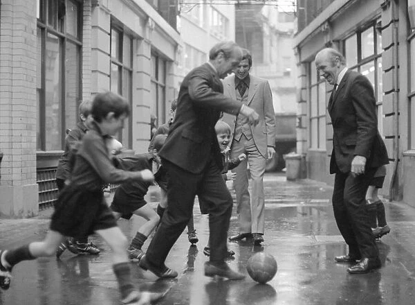 Manchester United and England footballer Bobby Charlton is chased in the street by