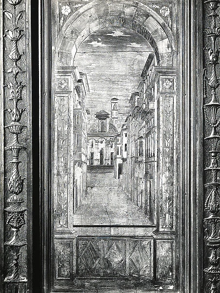 Trompe-l'oeil with an urban road delimited by high buildings. At the end, a church front. Inlaid work by Fra Giovanni da Verona, in the choir stall of the Abbey of Monte Oliveto Maggiore, in Chiusure, in the environs of Siena