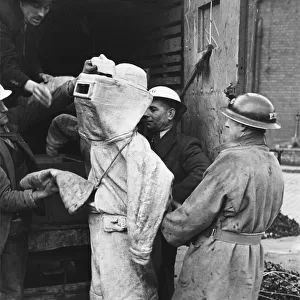 Firefighter putting on his asbestos suit in England during the air raids of World War II