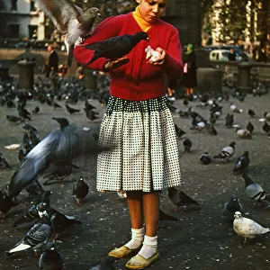 Girl feeding pigeons in Trafalgar Square, London