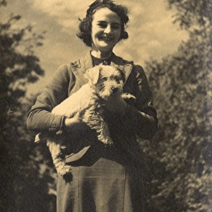 Woman holding a dog in a garden