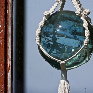 Old-fashioned glass float used in fishing nets hangs in window near Latrabjerg, Iceland
