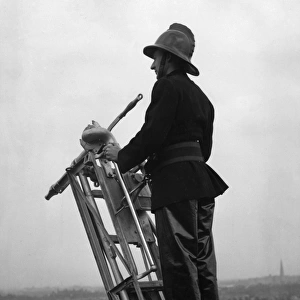 Firefighter using hook belt at top of ladder