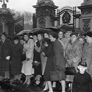 Women with umbrellas and macintoshes waited outside Buckingham Palace in the rain