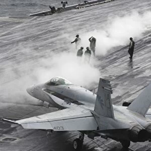 An F / A-18C Hornet taxies to a steam-powered catapult on the flight deck of USS Theodore