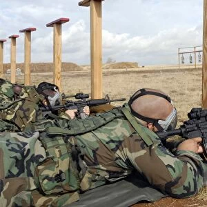 Soldiers sight M-4 rifles down range while wearing MCU-2 protective gas masks
