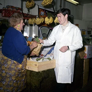 Arsenal footballer Pat Rice serves a customer while working on his London fruit stall