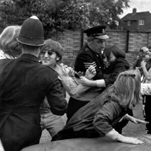 John Lennon of The Beatles being mobbed by fans at London Airport. 8th August 1966