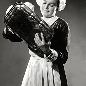 A maid polishing a silver tray, March 1938